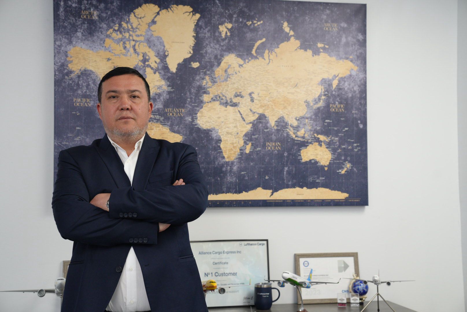 Kamalbek Jurayev in his office with a world map and logistics awards